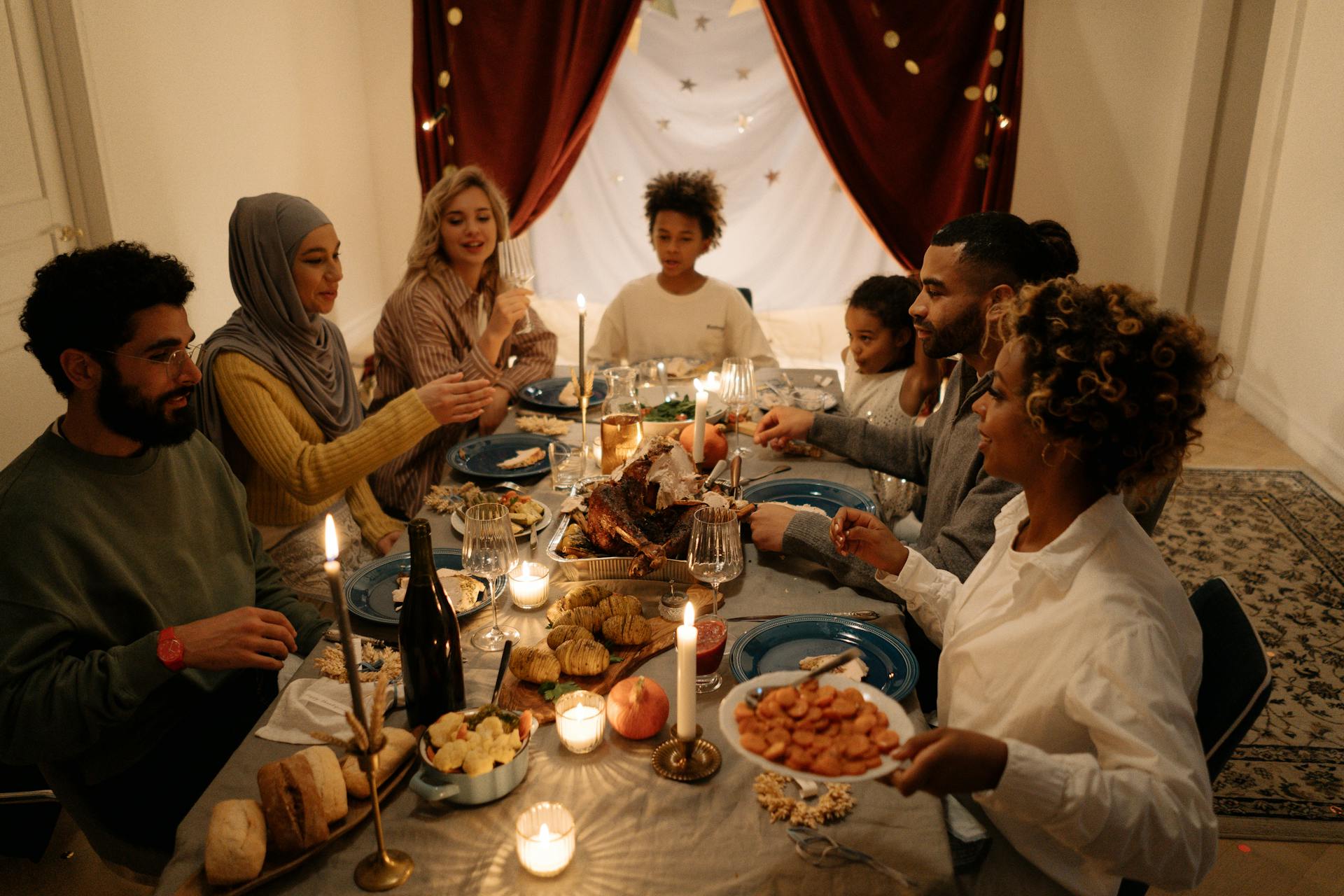 A diverse group of friends sharing a festive dinner, surrounded by warm candlelight and decorations guided by thanksgiving conversations tips from Nick Lenzi