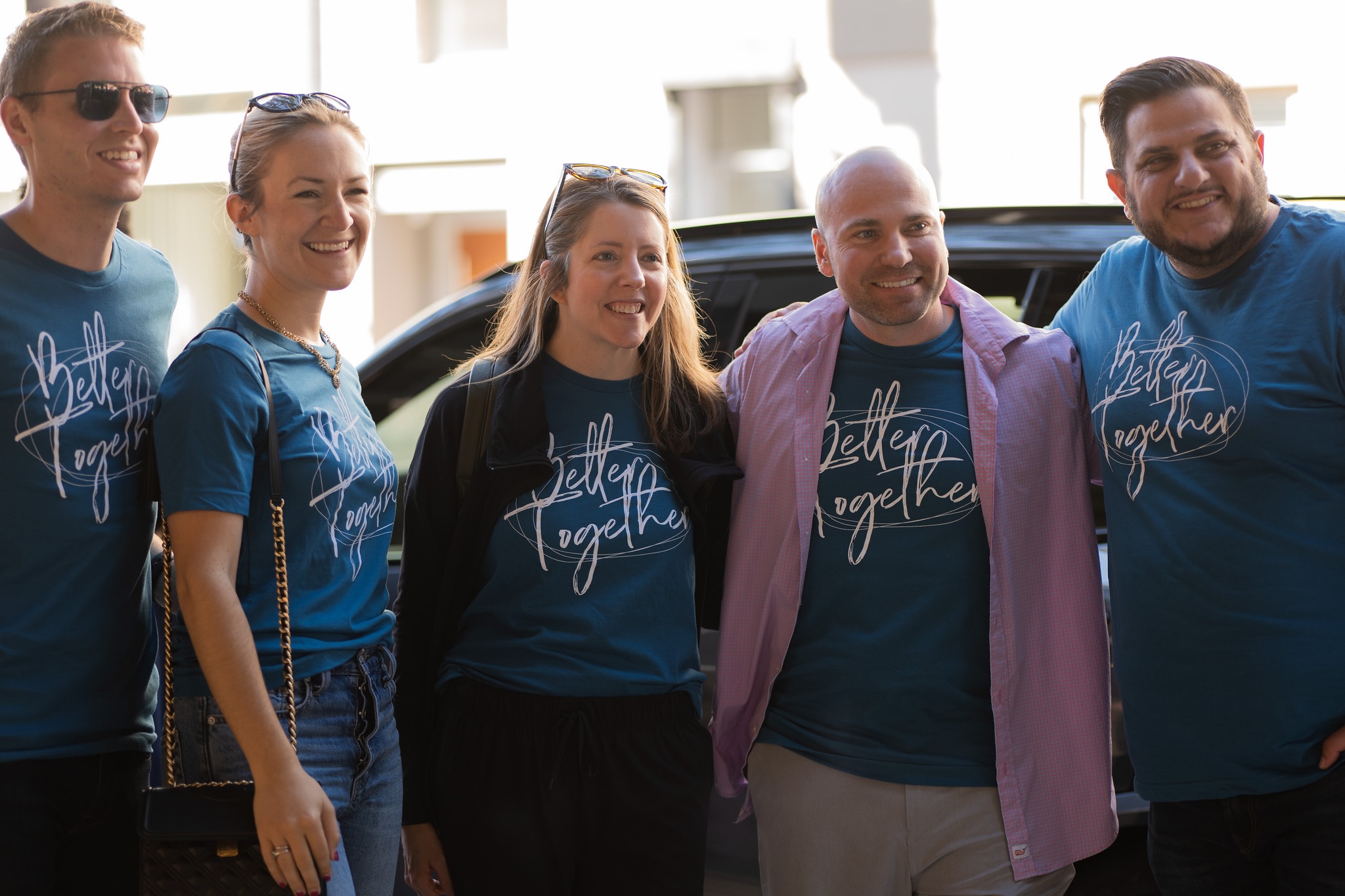 Group of Hoboken Grace team members wearing ‘Better Together’ t-shirts, smiling and standing outdoors.