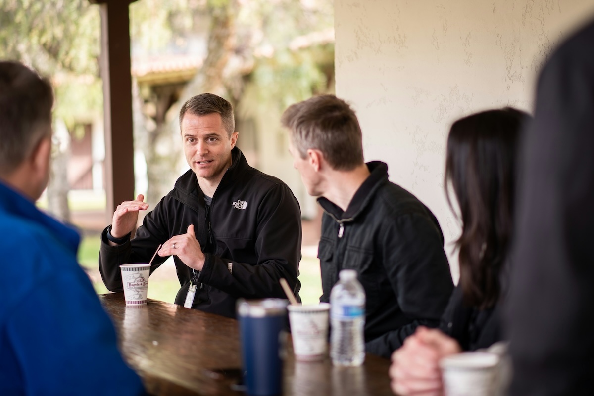 Small group leader facilitating an outdoor discussion with group members, engaging in a conversation.